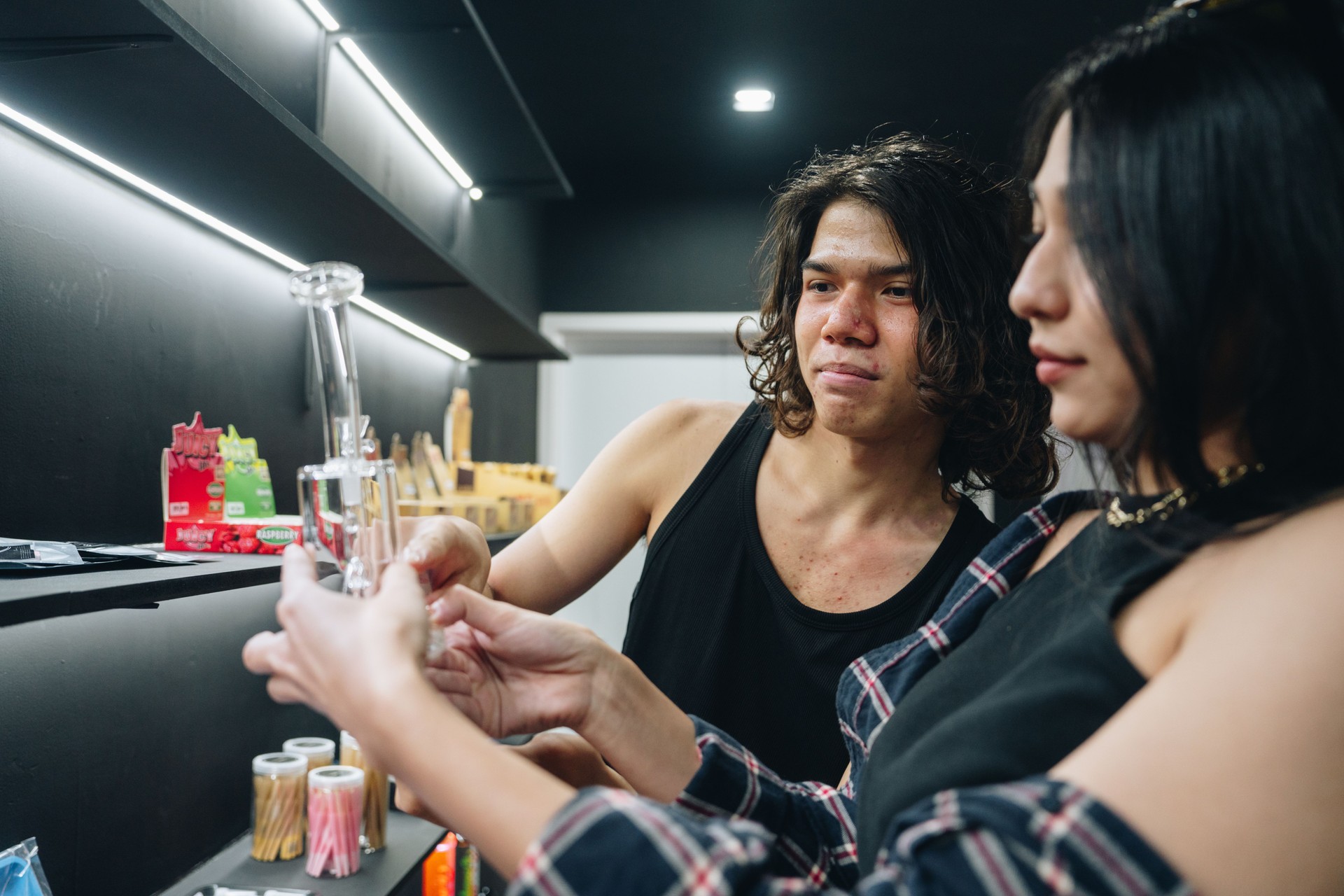 Young man helping a customer while she shop in his organic cannabis store.